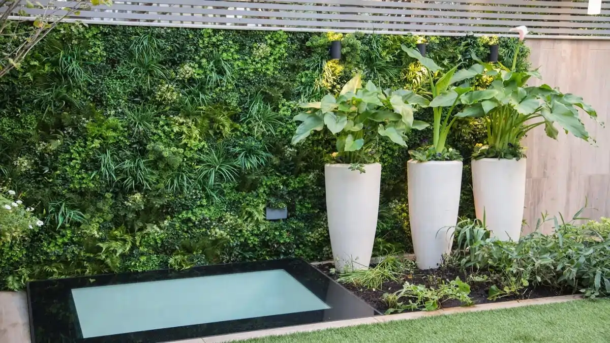 Uma parede verde com plantas artificiais feita na sala da casa. Dicas no Blog Conversa Pronta.