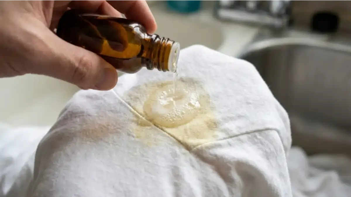 Mão aplicando solução caseira para tirar mancha no blog Conversa Pronta.