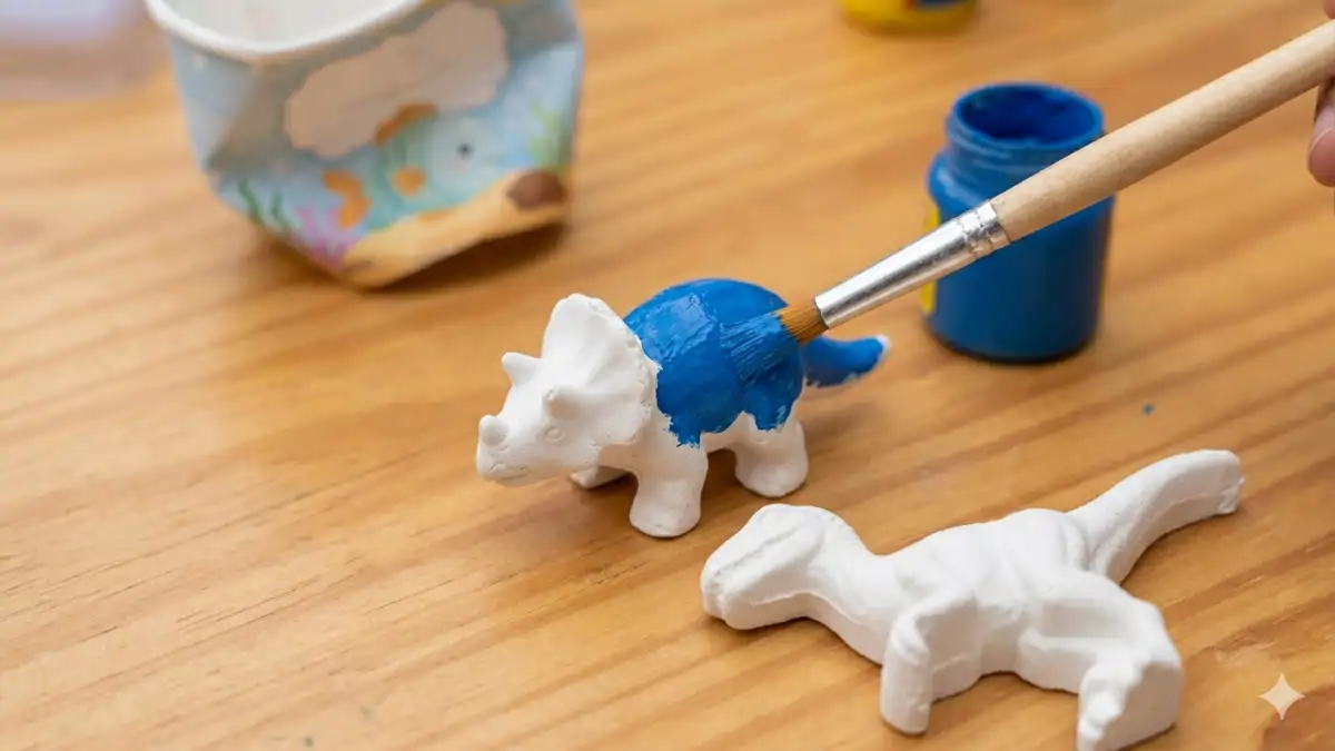 Pintura azul sendo feita em um dinossauro de gesso no blog Conversa Pronta.